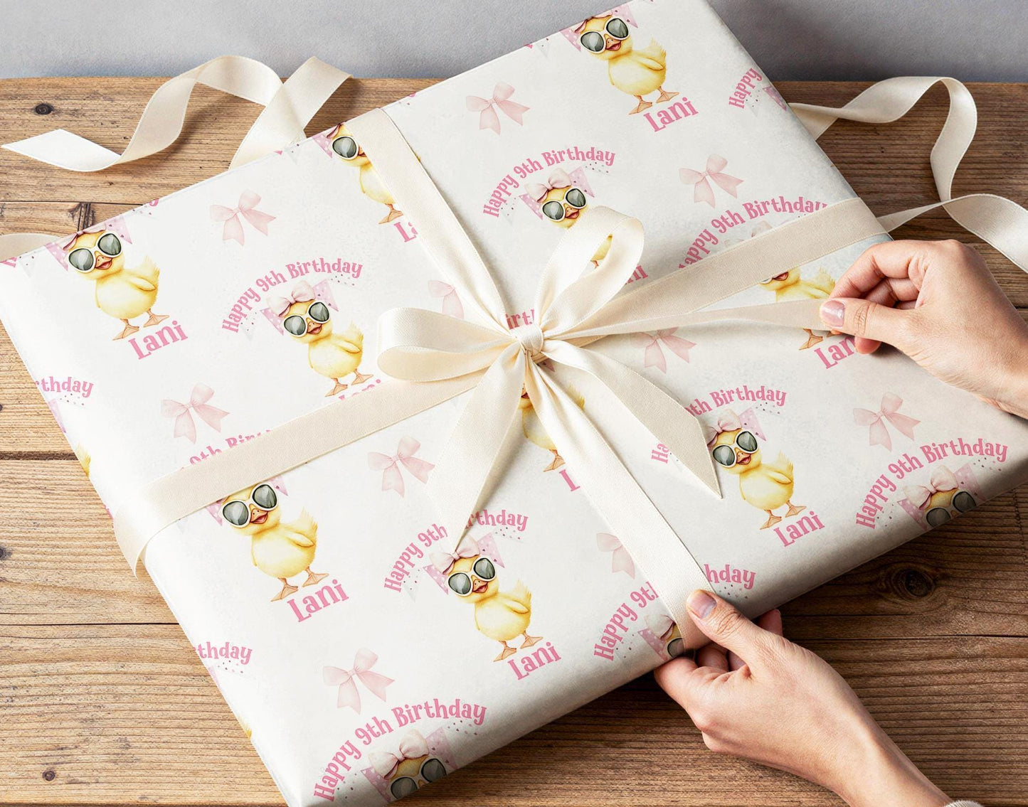 Close-up of the personalised sunglasses duck wrapping paper with a custom name and age, on a pink background