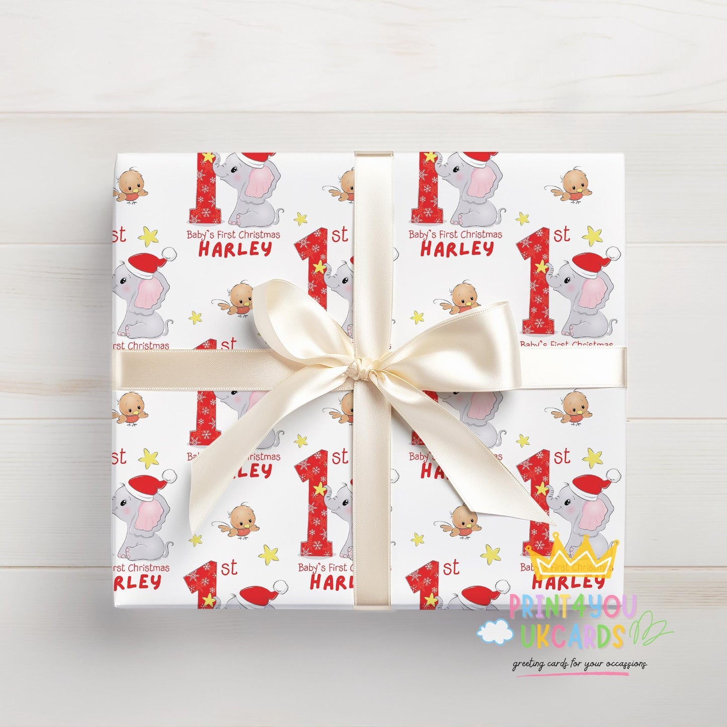 Wrapped gift box in personalised Baby's First Christmas elephant wrapping paper with a custom name and white ribbon.
