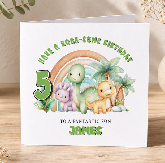 Square birthday card featuring an illustrated dinosaur and rainbow, reading 'Have a Roar-Some Birthday' and 'To a Fantastic Son, James'.