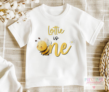 White toddler sweatshirt in size 1-2 years personalised with a name and a Bee is One bumblebee and daisy first birthday design