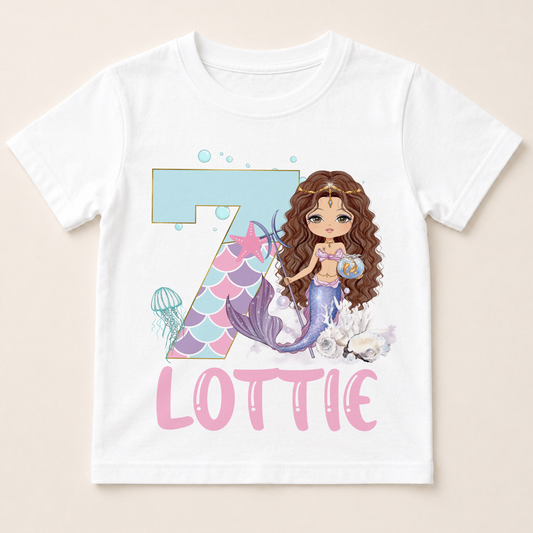 A white t-shirt with a mermaid graphic and the number 7, along with the text "LOTTIE" below it.