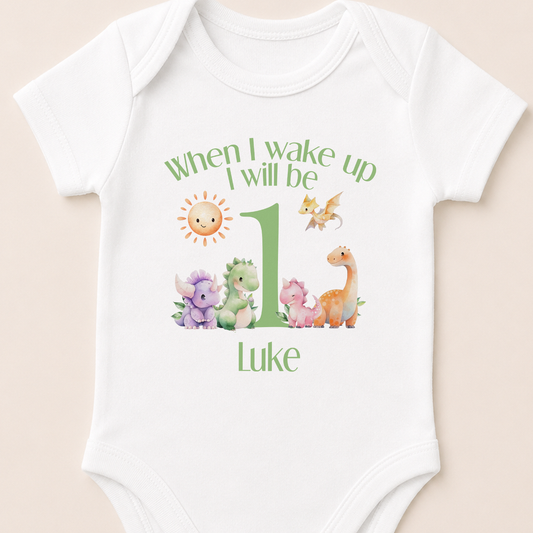White baby onesie personalised with 'When I Wake Up I Will Be One' and a green dinosaur design