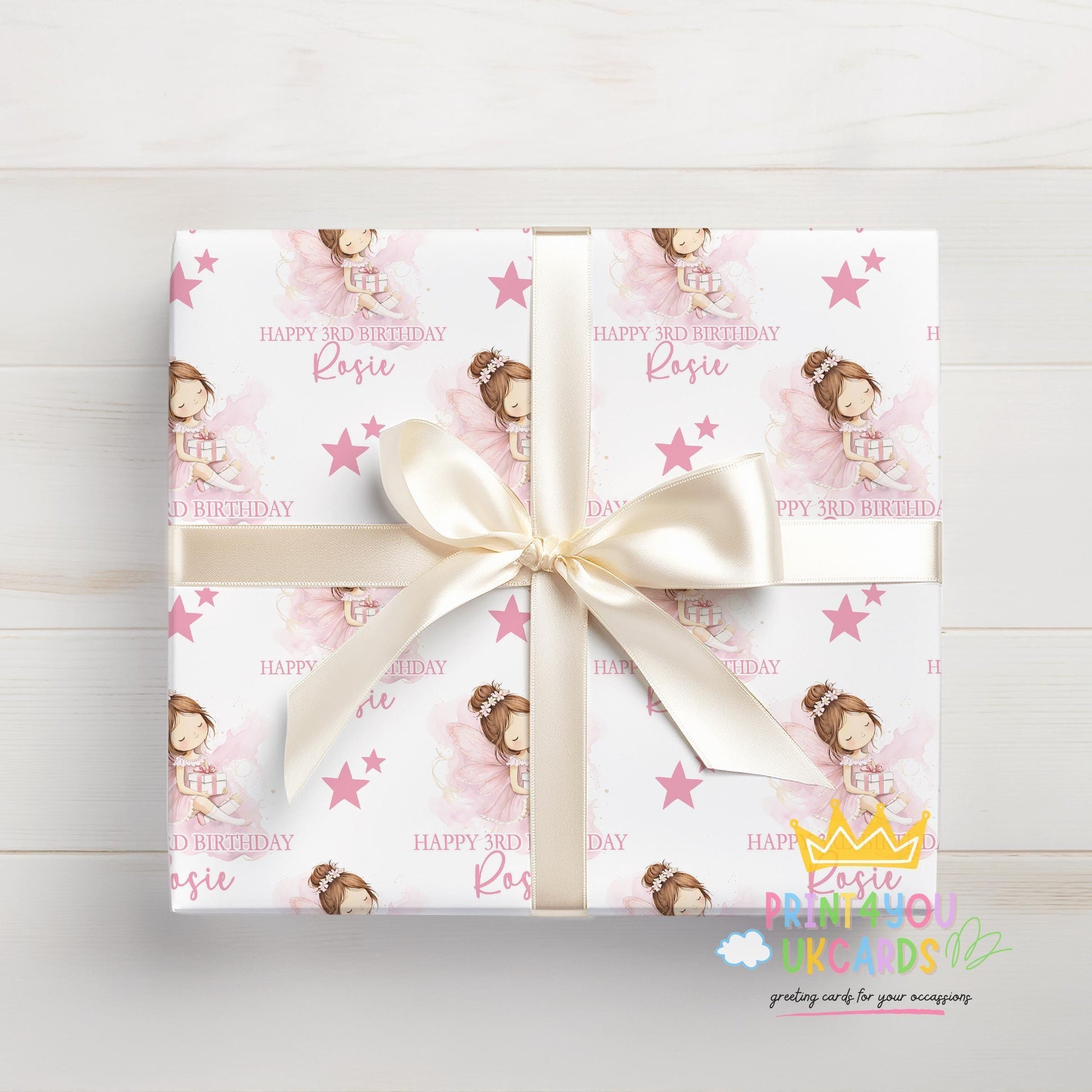 Wrapped gift box finished in the pink fairy and stars personalised wrapping paper, tied with a white ribbon.