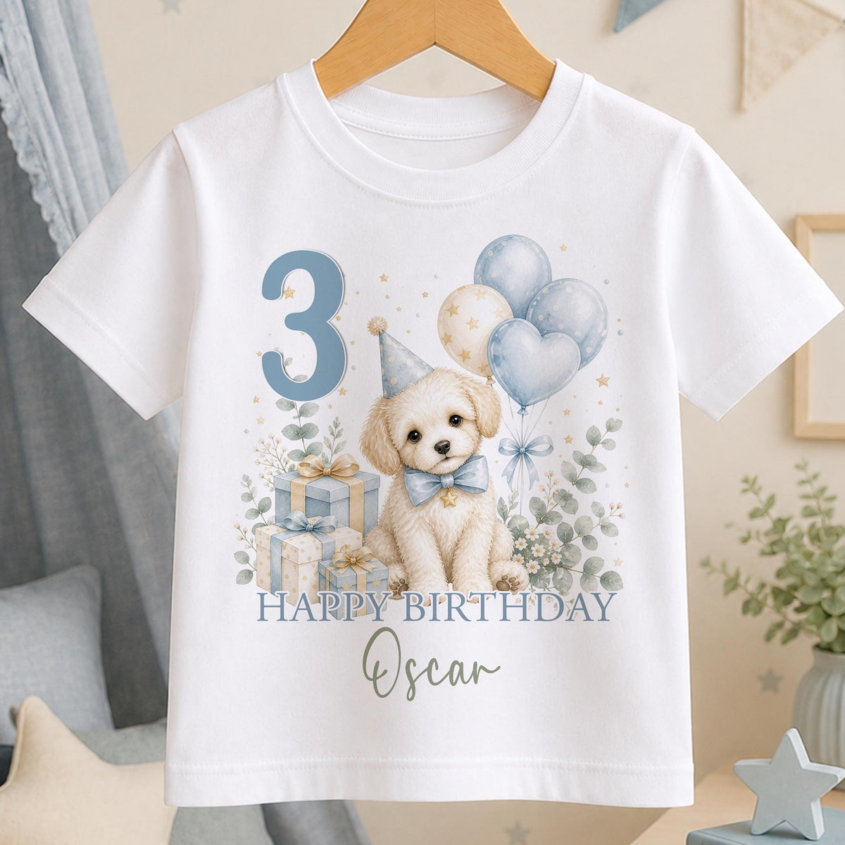 Personalised birthday t-shirt in white cotton with a cream puppy in a blue party hat, blue balloons and Happy Birthday with a name and age