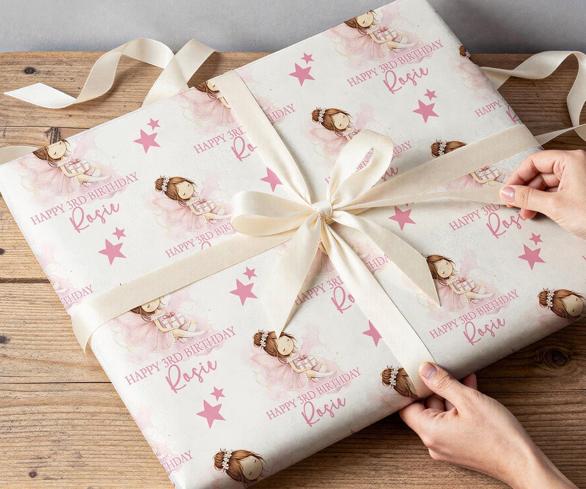 Gift being wrapped in personalised pink fairy birthday wrapping paper with a white ribbon bow.