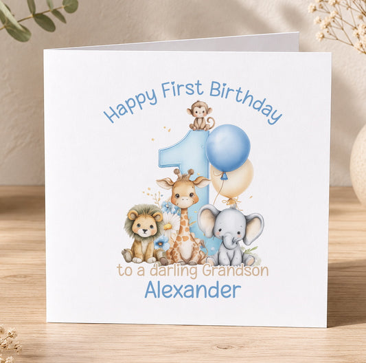 A white greeting card with a cartoon illustration of various animals, including a lion, giraffe, elephant, and monkey, along with a blue balloon. The text on the card reads "Happy First Birthday to a daring Grandson Alexander".