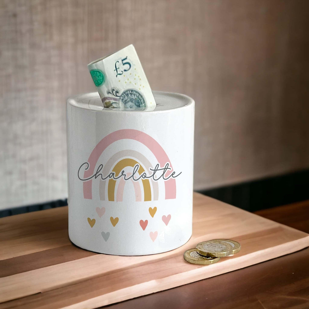 Personalised rainbow money box for Charlotte with a five pound note in the coin slot
