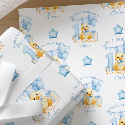 Close-up of personalised first birthday wrapping paper featuring a cute duckling, blue number one, balloons and presents on premium white wrapping paper.
