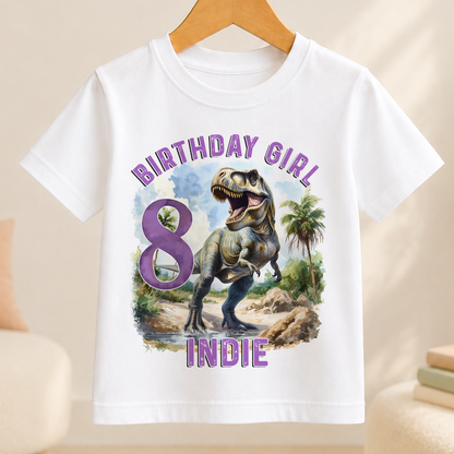 A white t-shirt with a graphic design featuring a dinosaur and the text "BIRTHDAY GIRL 8 INDIE" printed on it.