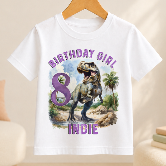 A white t-shirt with a graphic design featuring a dinosaur and the text "BIRTHDAY GIRL 8 INDIE" printed on it.