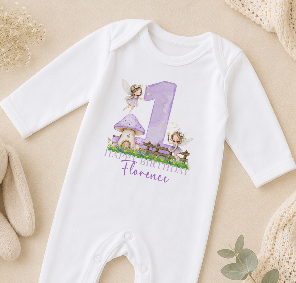 A white onesie with a purple number 1 and a fairy design, along with the text "Happy Birthday Florence" printed on it.