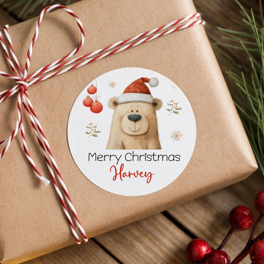 Gift box wrapped in red and white ribbon finished with a personalised glossy round Santa bear Christmas sticker printed with a custom name