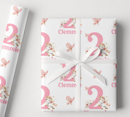 A gift wrapped in personalised pink and white unicorn wrapping paper, finished with a white ribbon