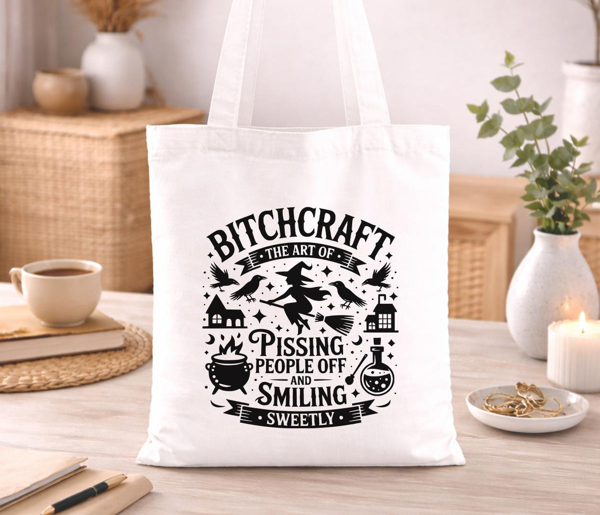 Black cotton tote bag printed with a gothic witch illustration and the slogan 'Bitchcraft' in bold lettering