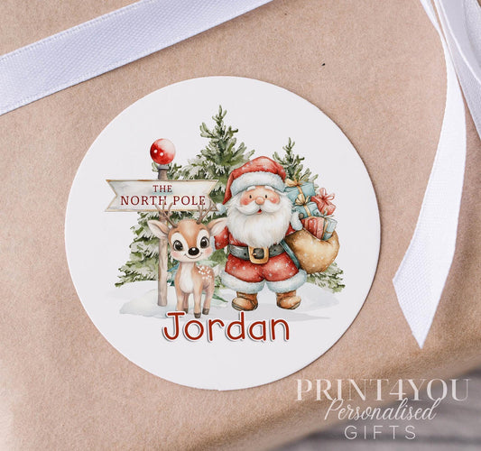 Personalised Santa and reindeer Christmas sticker in a fun winter colour palette, custom name printed on a glossy round gift label strip