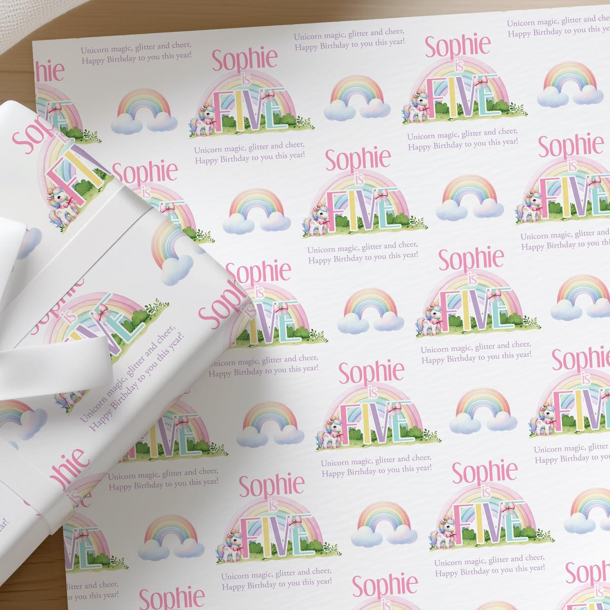 Roll of personalised rainbow unicorn birthday wrapping paper printed with a name and age