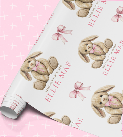 a roll of wrapping paper with a repeating pattern of a brown teddy bear wearing a pink bow.