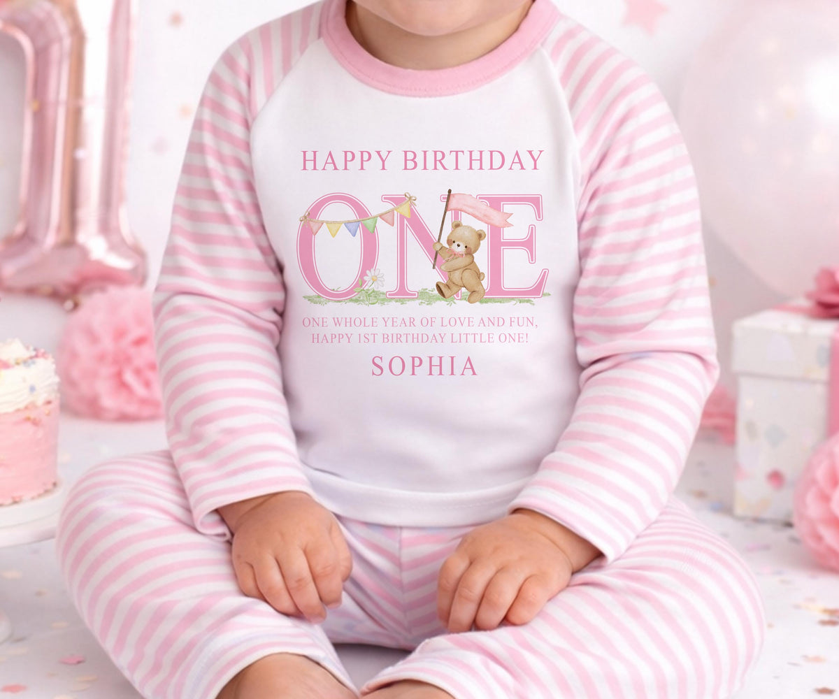 Personalised first birthday pyjamas in a pink striped design with the baby's name printed on the front.