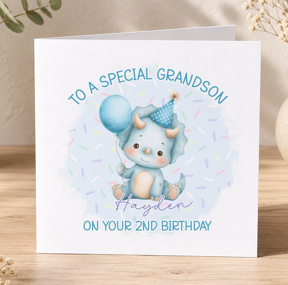 Square personalised dinosaur birthday card featuring a blue triceratops in a party hat holding a balloon, with the recipient's name and age printed on the front.