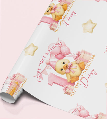 Roll of personalised first birthday wrapping paper featuring a repeating pink duckling, number one and birthday balloon design.