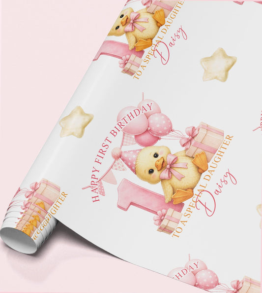 Roll of personalised first birthday wrapping paper featuring a repeating pink duckling, number one and birthday balloon design.