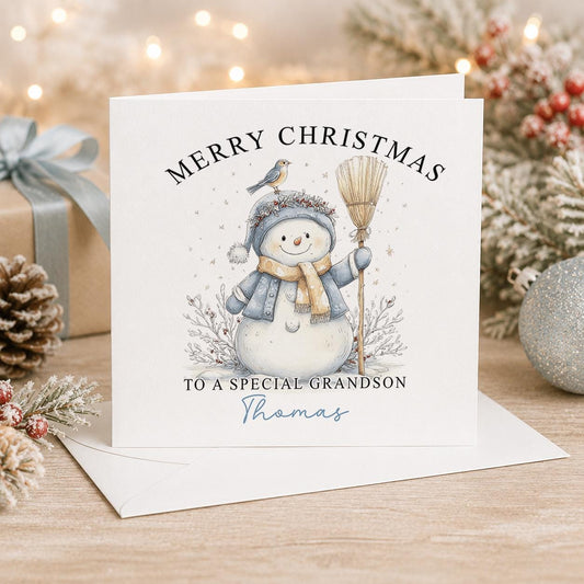 Personalised snowman Christmas card, white 6x6 inch square card printed with a snowman in a blue scarf holding a broom with a name