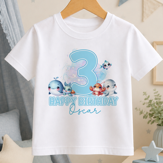 White cotton birthday t-shirt printed with a large number 3, a whale, a crab and fish, personalised with a child's name