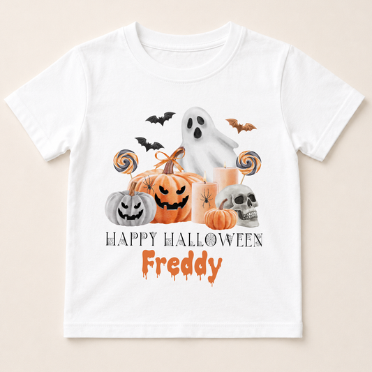 A white t-shirt with a Halloween-themed graphic design featuring a ghost, pumpkins, a skeleton, and bats. The text below the graphic says "Happy Halloween Freddy".