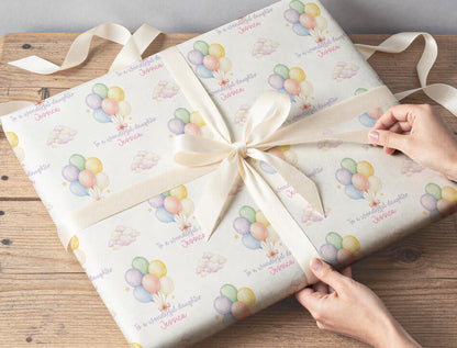 A wrapped gift box finished with ribbon, wrapped in the pastel balloon and cloud wrapping paper