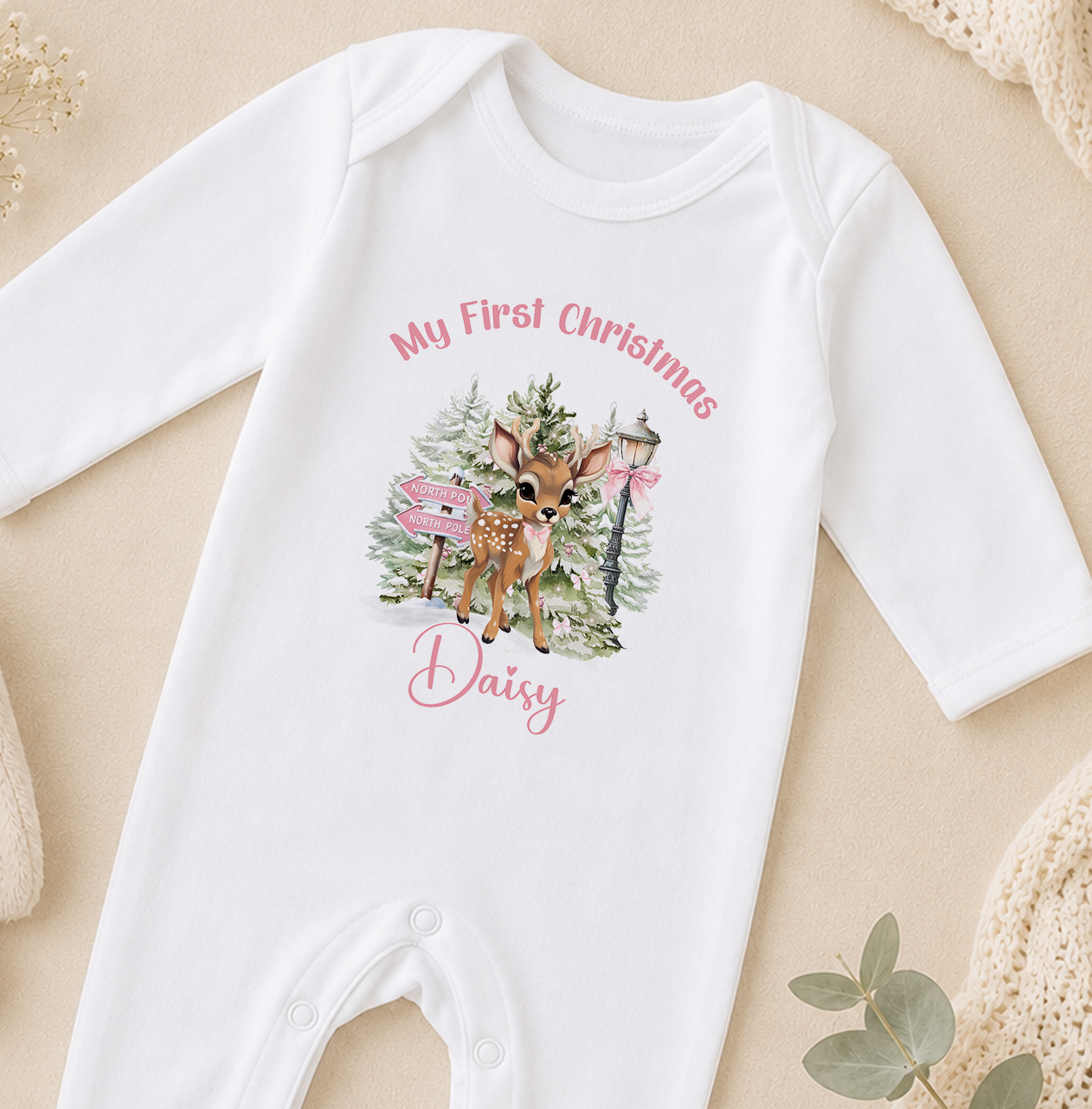 A white onesie with a printed image of a deer and Christmas decorations, along with the text "My first Christmas Daisy".
