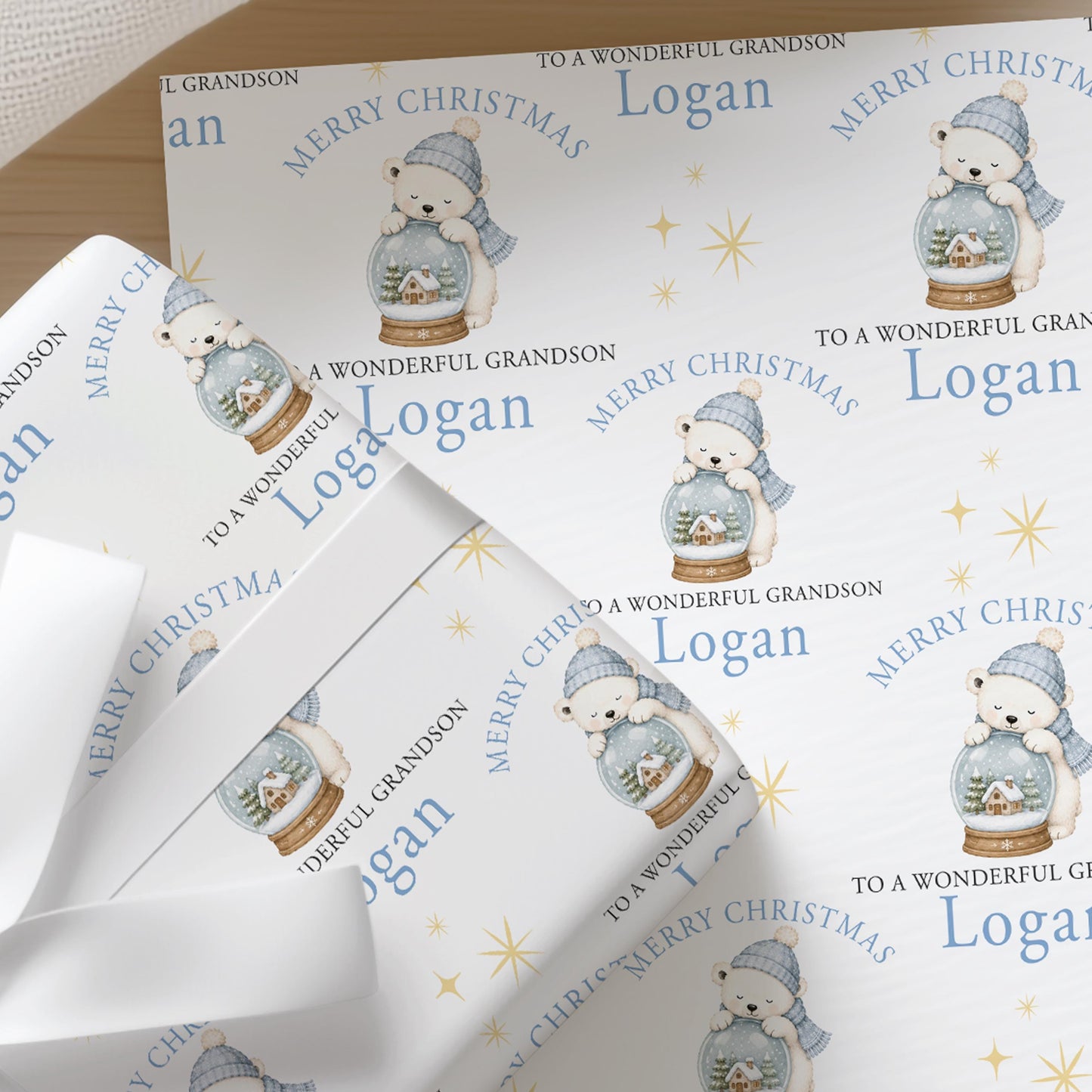 Personalised Christmas wrapping paper featuring a polar bear inside a snow globe, with a custom name printed across the design.