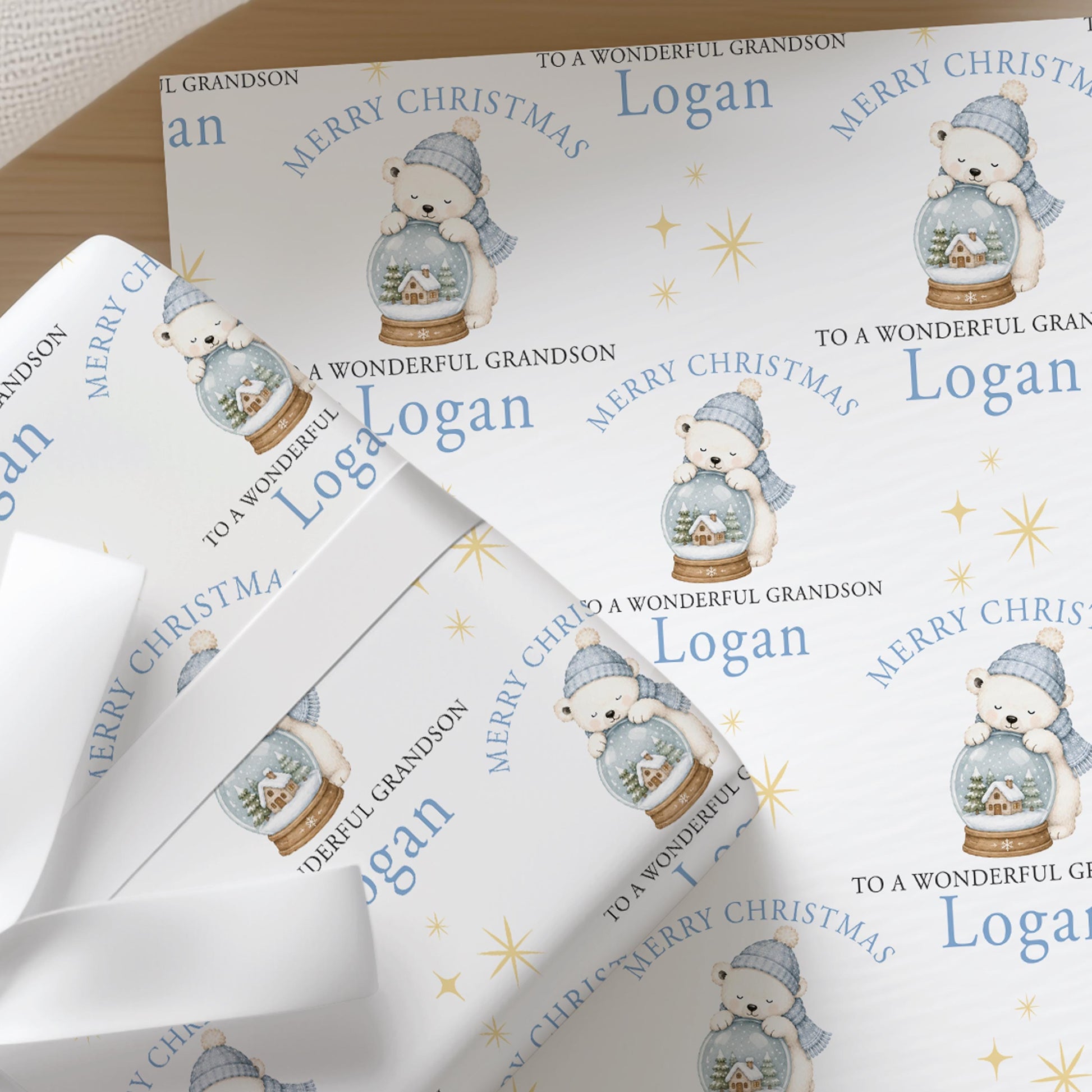 Personalised Christmas wrapping paper featuring a polar bear inside a snow globe, with a custom name printed across the design.