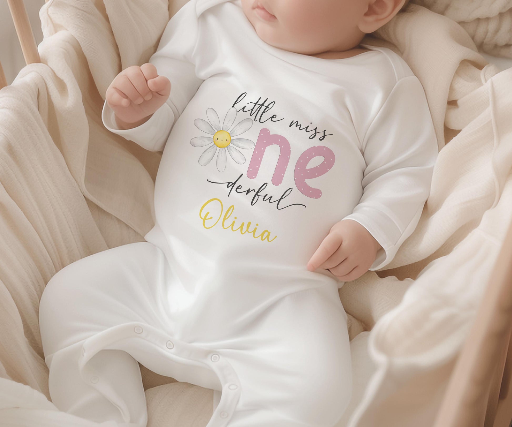 Personalised first birthday sleepsuit with daisy party design and custom name, soft cotton.