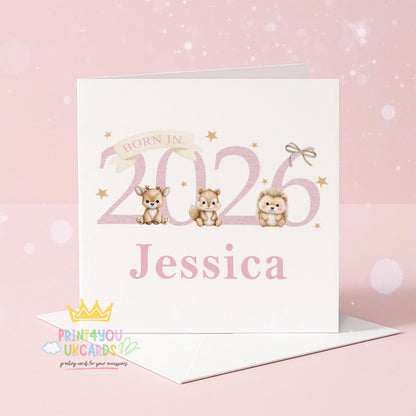 White square newborn card standing on a wooden surface with eucalyptus leaves, reading 'Born In 2026' with an illustrated deer, chipmunk and hedgehog, personalised with the name Jessica