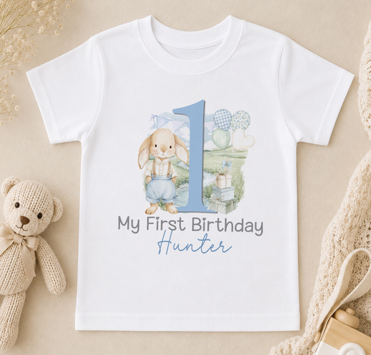 A white t-shirt with a printed design featuring a rabbit and the number 1, along with the text "My First Birthday Hunter".