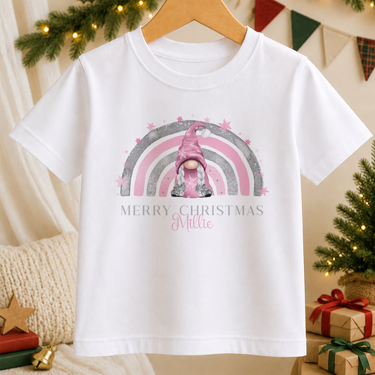 A white t-shirt with a graphic design featuring a pink gnome and a rainbow, along with the text "Merry Christmas Millee" printed on it.
