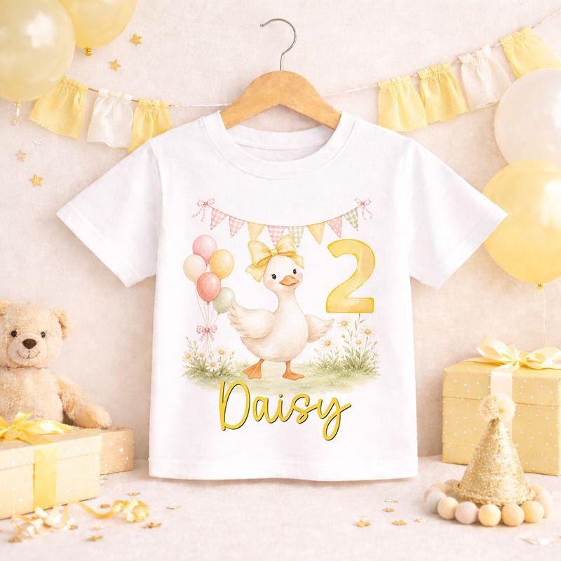 Personalised duck birthday shirt for kids laid flat, featuring a duckling party design with space for the child's name and age.