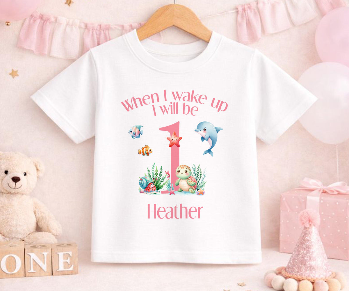 Personalised first birthday sleepsuit with custom name, laid flat to show the print.