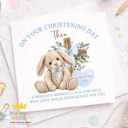 Square christening card featuring a blue bunny illustration and a wooden cross, personalised with a baby boy's name