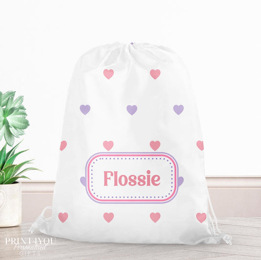White drawstring PE bag scattered with pink and purple hearts, personalised with a child's name across the front
