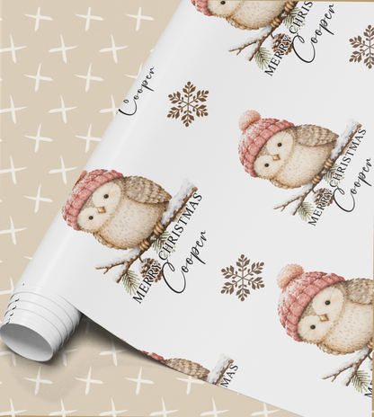 a white wrapping paper with a repeating pattern of cute owls wearing winter hats and holding pine branches. The owls are wearing red hats and are surrounded by snowflakes. The paper has the text "Merry Christmas Copper" written on it, indicating a festive holiday theme.
