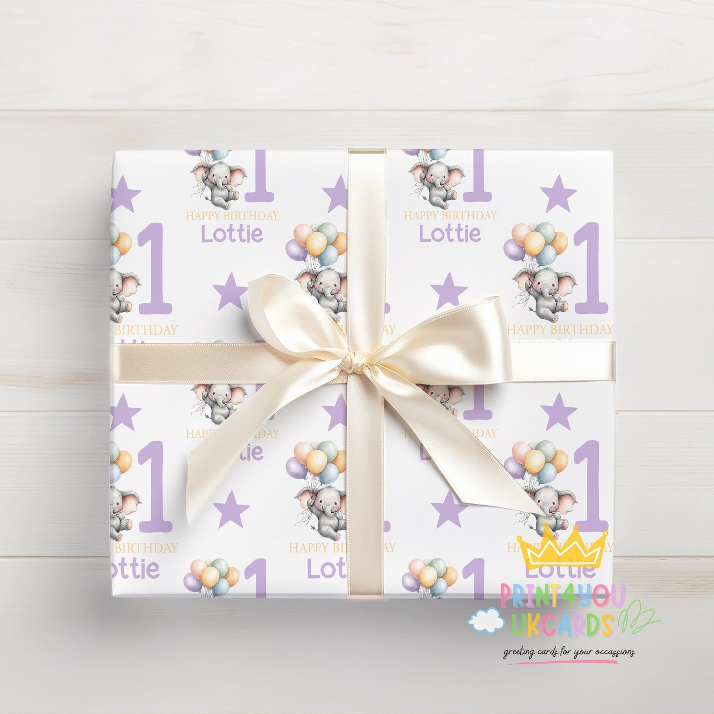 Personalised purple elephant birthday wrapping paper shown rolled and tied with ribbon.
