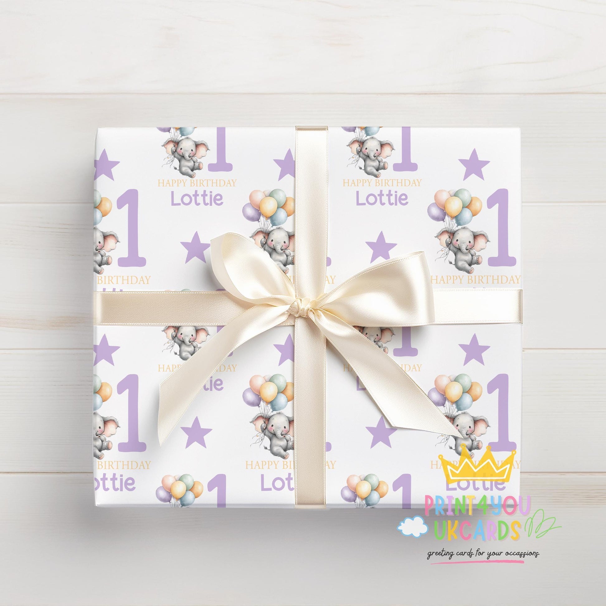 Personalised purple elephant birthday wrapping paper shown rolled and tied with ribbon.