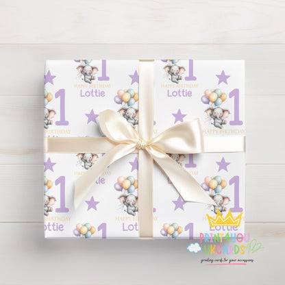 Personalised purple elephant birthday wrapping paper shown rolled and tied with ribbon.