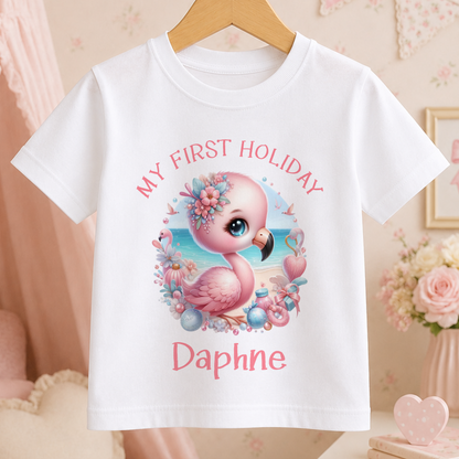 A white t-shirt with a pink flamingo graphic and the text "My first holiday Daphne" printed on it.