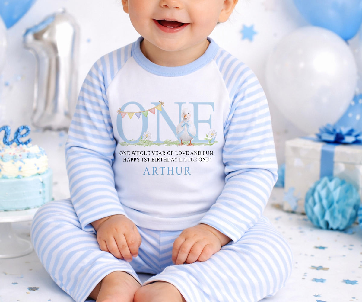 Personalised first birthday pyjamas with blue duck design and custom name, soft cotton.