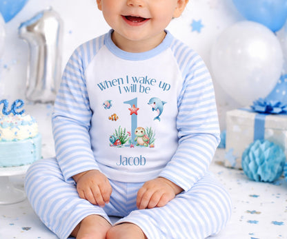 Personalised first birthday pyjamas with a blue under-the-sea design and the baby's name printed on the front.
