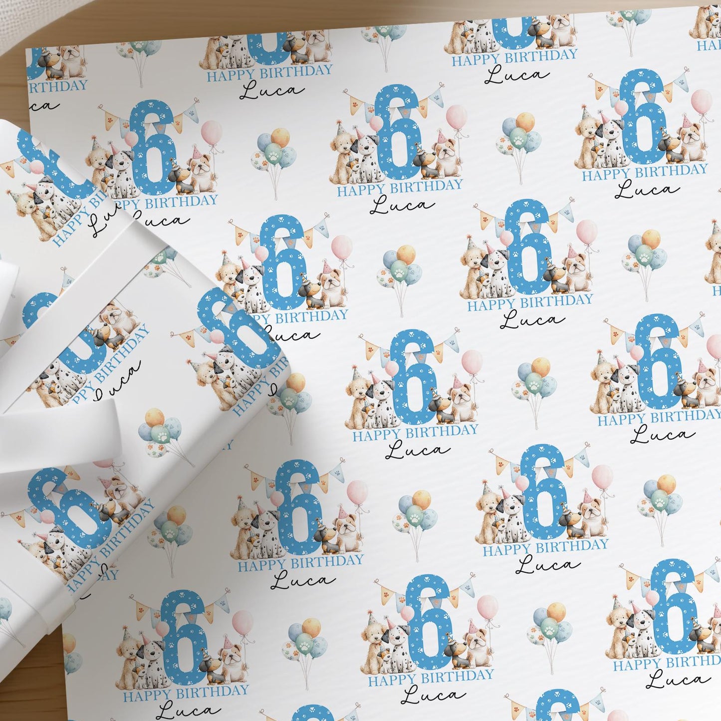 Flat lay of personalised dog birthday wrapping paper with a name and age printed across the sheet