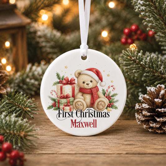 Personalised baby first Christmas bauble, white ceramic ornament with a teddy bear in a Santa hat and red presents, printed with First Christmas and a name