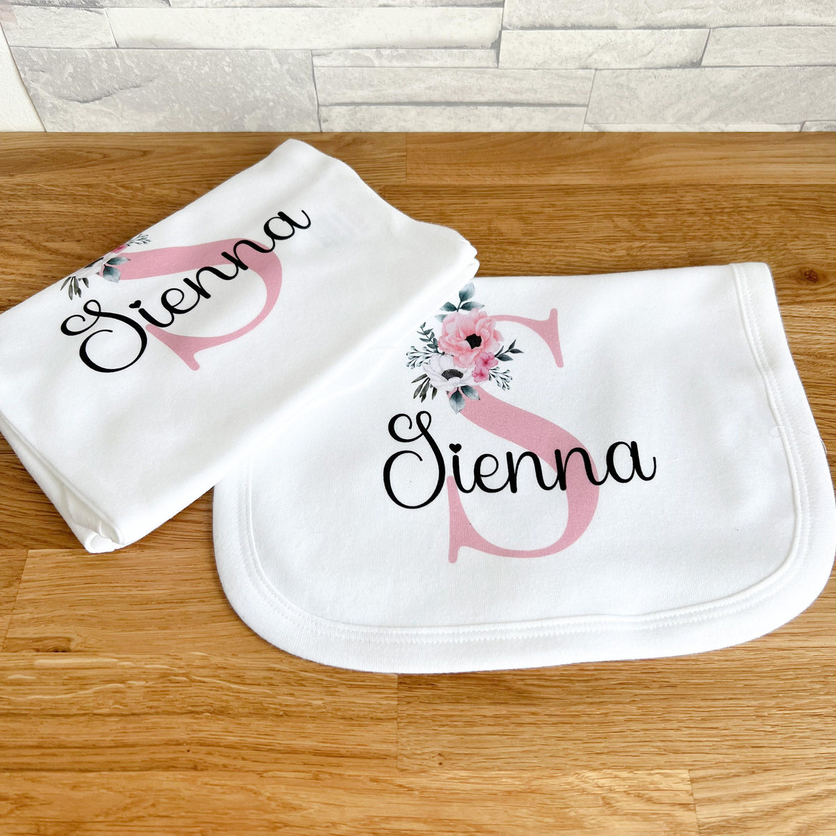 Personalised pink floral initial baby sleepsuit, printed with the child's custom name.